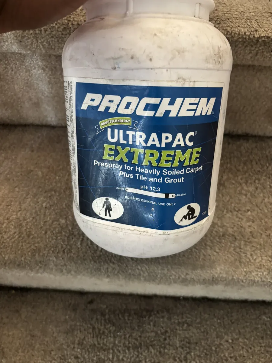 Prochem Ultrapac Extreme carpet pre-spray bottle held on a carpeted staircase
