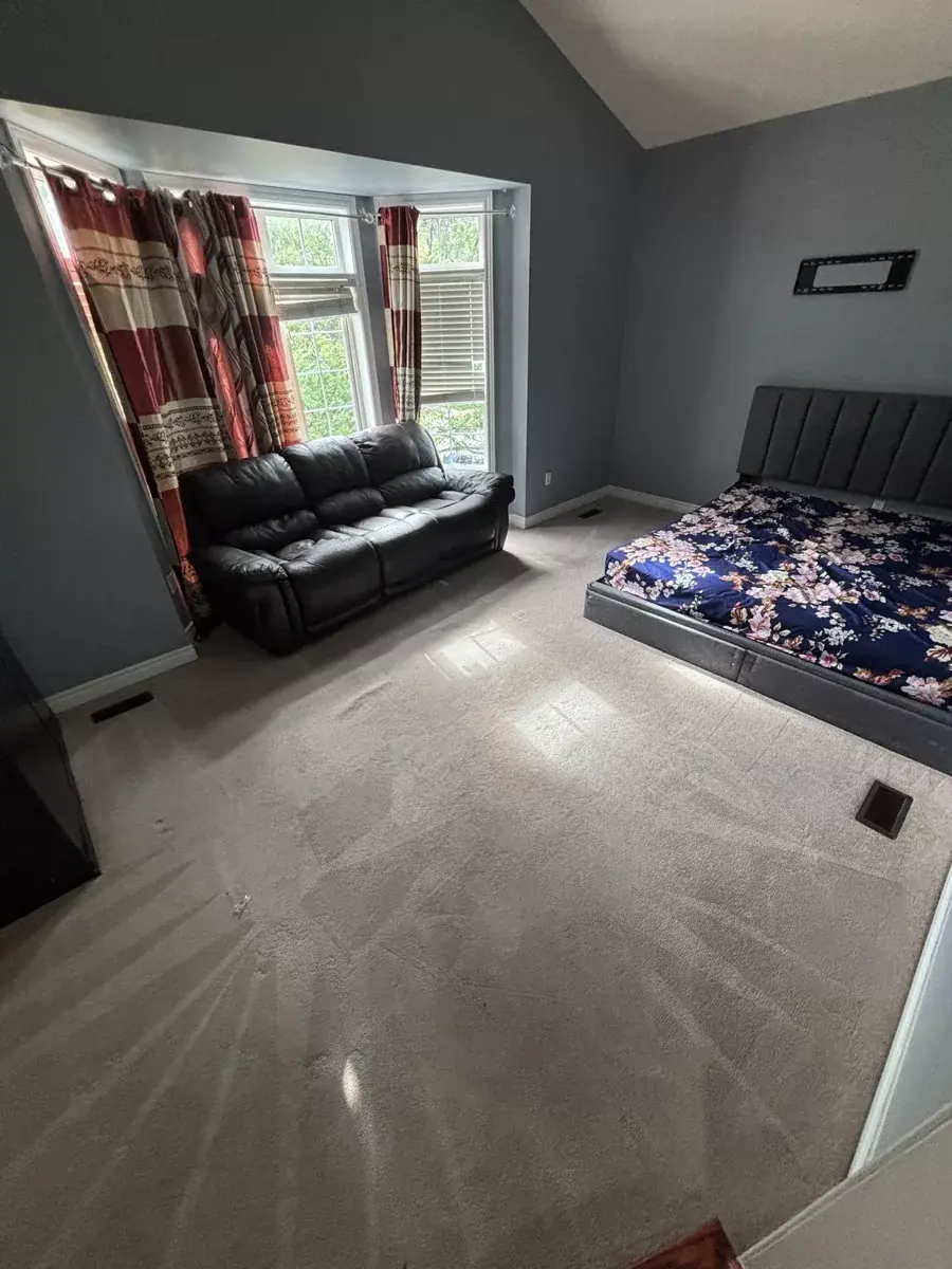 Furnished Brampton bedroom with freshly cleaned carpet, wand lanes visible across the pile, bed and leather sofa left in place