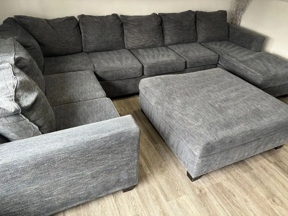 Technician using an upholstery attachment mid-clean on a fabric sofa